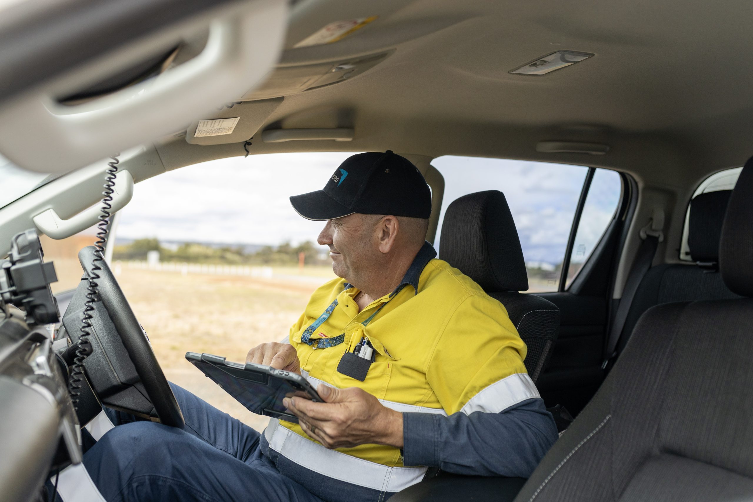 Engineer sitting in car with tablet taking notes.