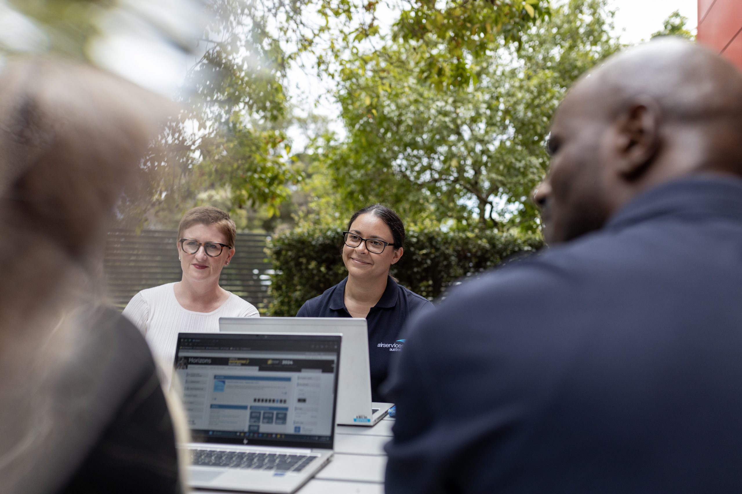 Airservices Australia colleagues discussing around a table outdoors
